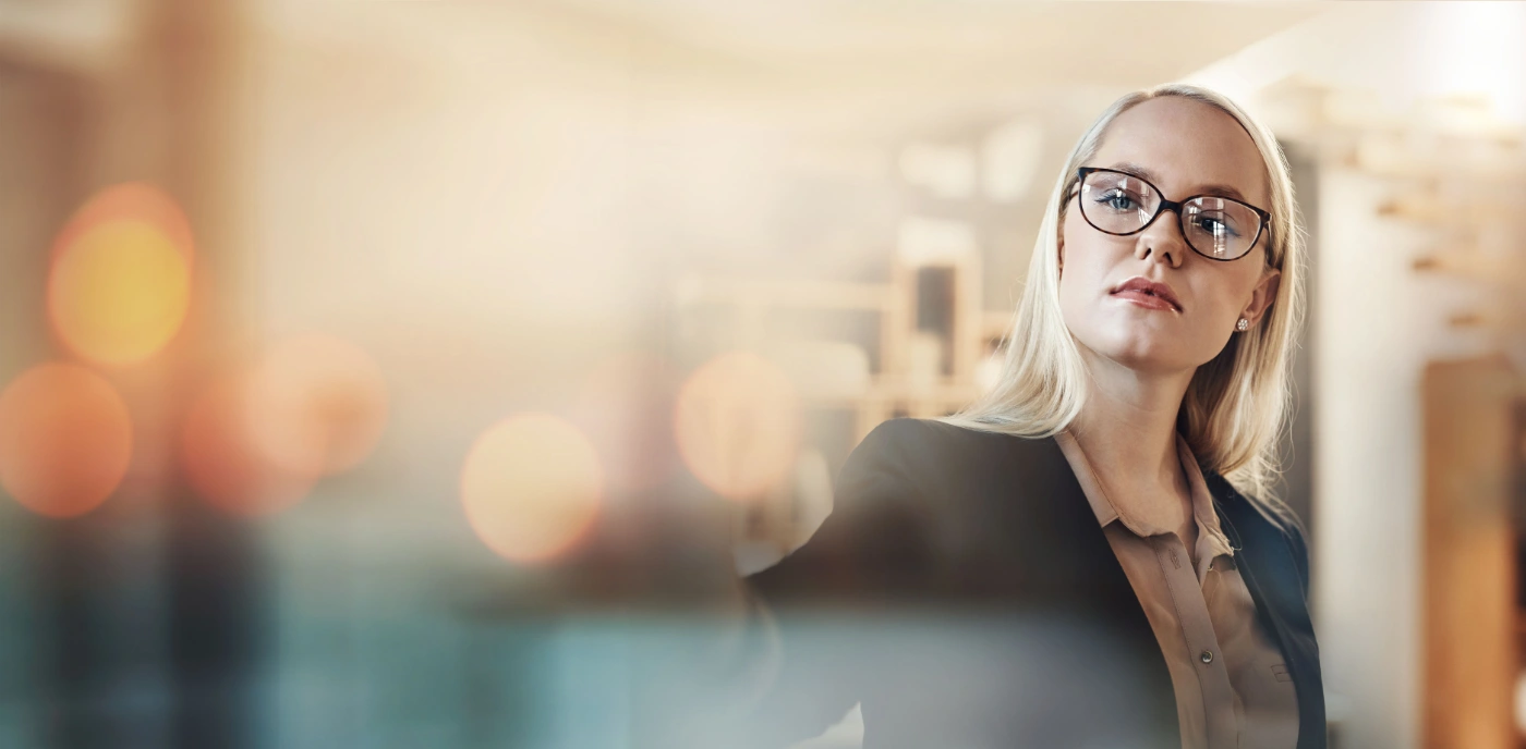 A woman standing in an office, looking away in thought