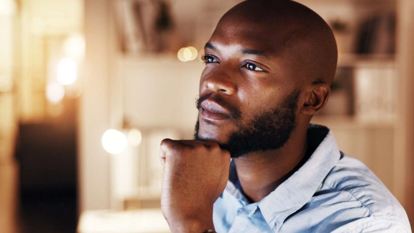A man sitting with his hand to his chin, considering his next step